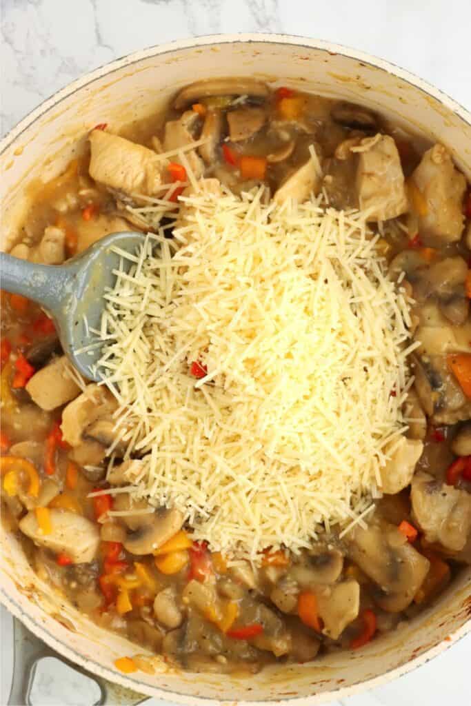 Overhead shot of chicken and vegetable mixture with parmesan cheese on top in pan. 