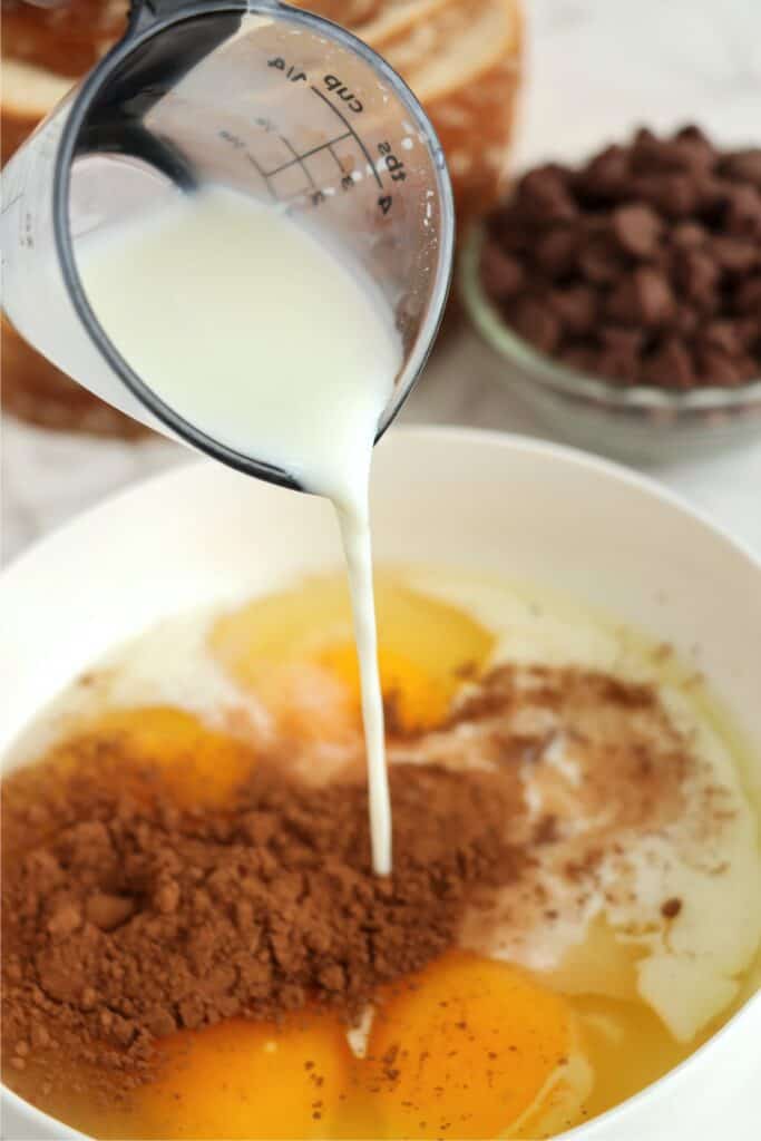 Milk being poured into bowlful of eggs and cocoa powder.