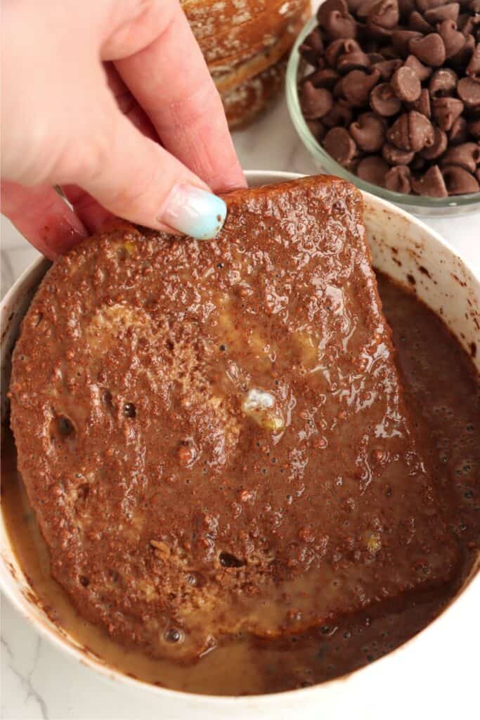 Closeup shot of bread being dipped into cocoa egg mixture