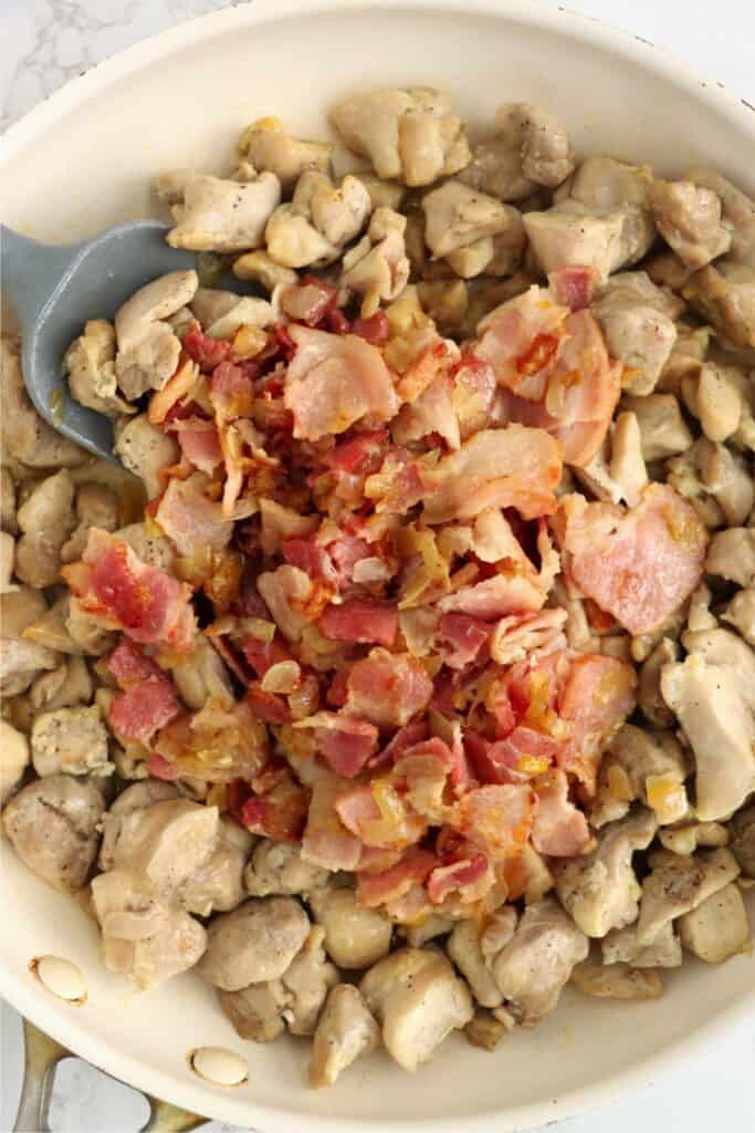 Closeup overhead shot of bacon, onions, and chicken in skillet