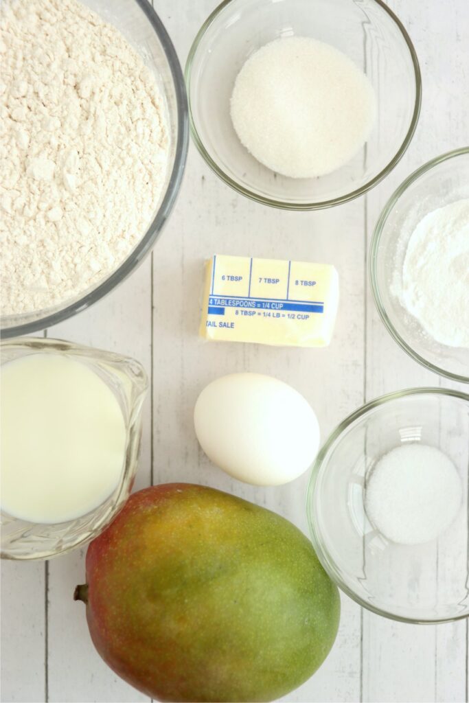 Overhead shot of individual mango pancake recipe ingredients in bowls on table