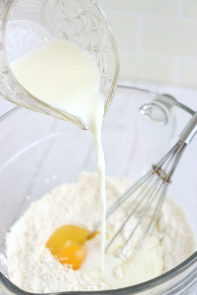 Milk being poured into bowl with pancake ingredients