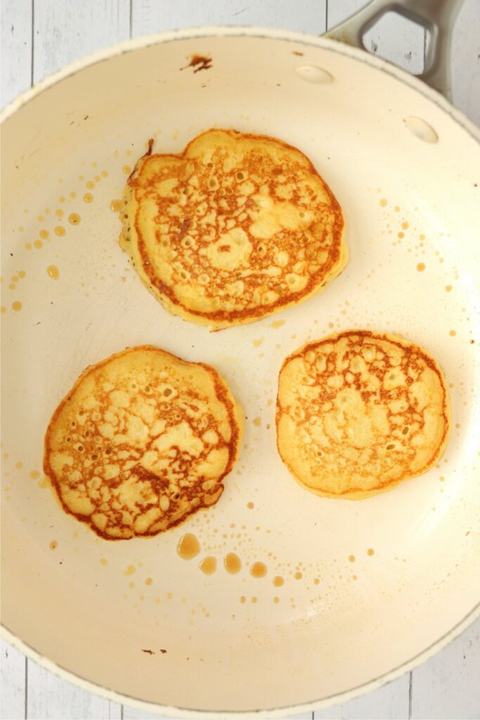 Overhead shot of golden brown mango pancakes in skillet