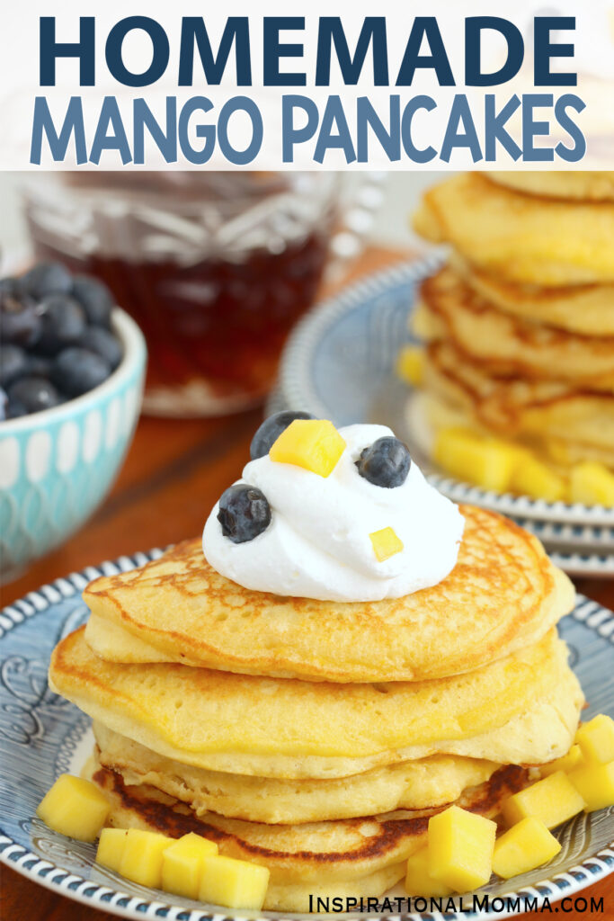 Mango pancake stack topped with whipped cream and berries on plate.