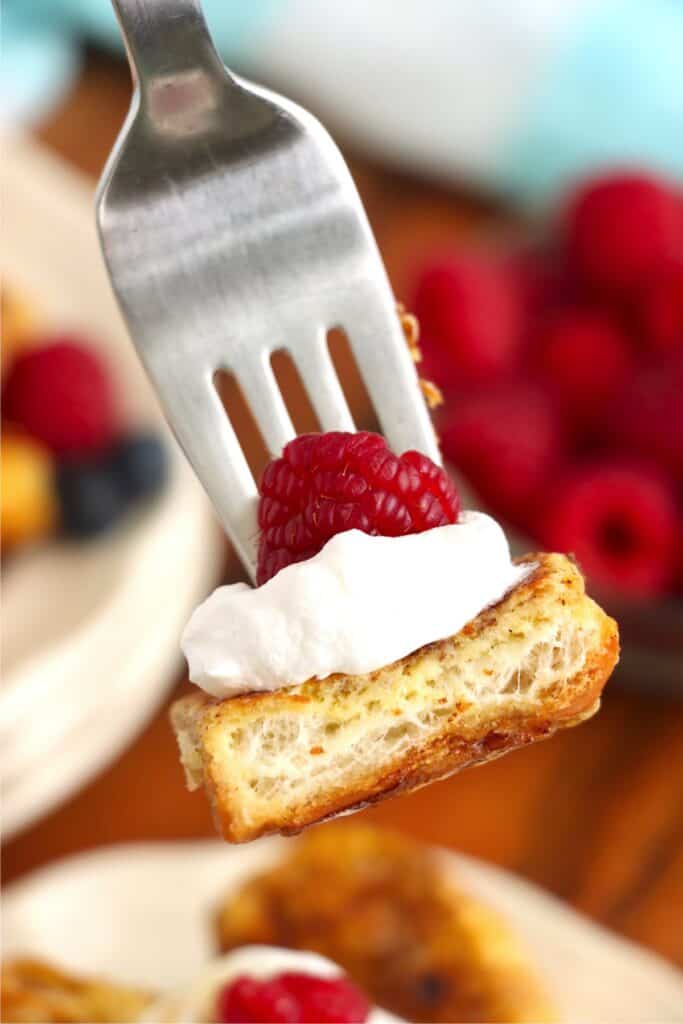 Closeup shot of forkful of hot dog bun French toast topped with whipped cream. 