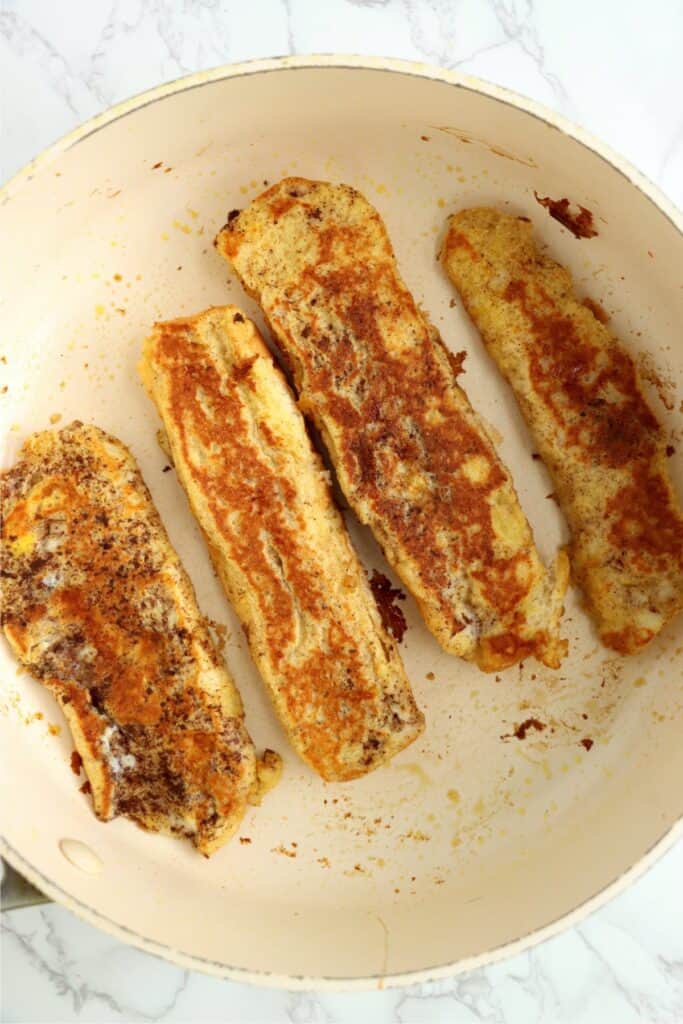 Overhead shot of golden bown hot dog bun French toast in skillet