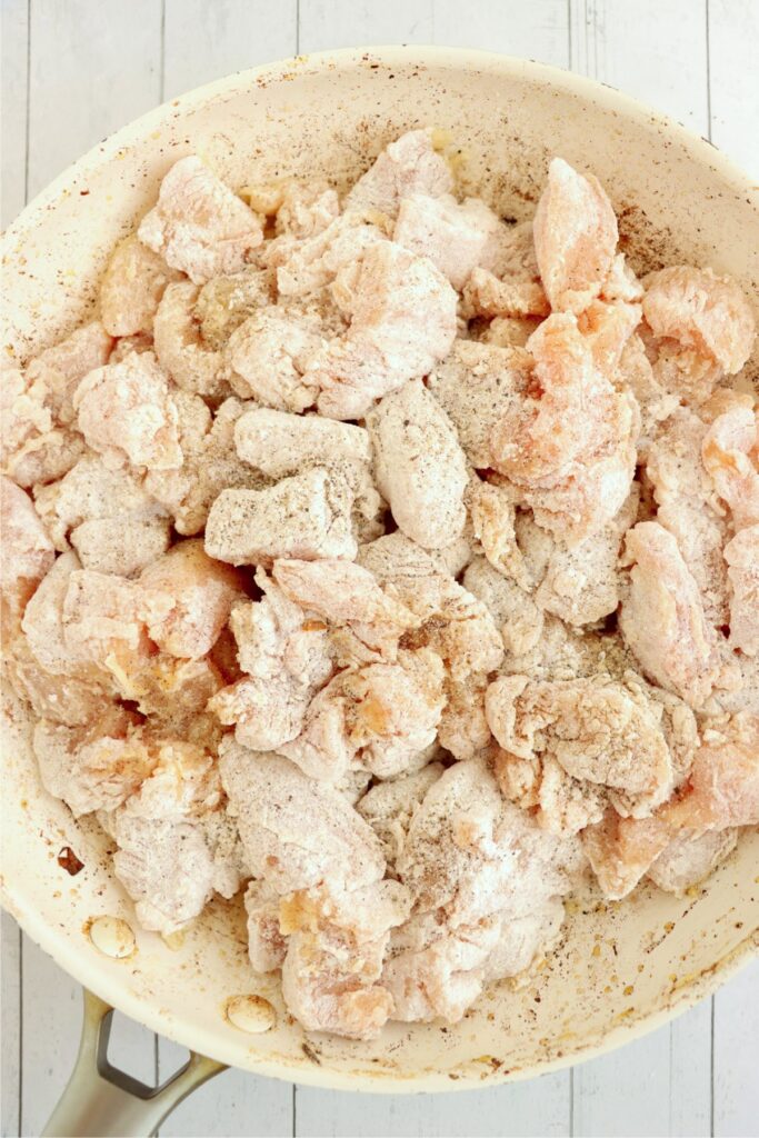 Overhead shot of floured chicken chunks in skillet