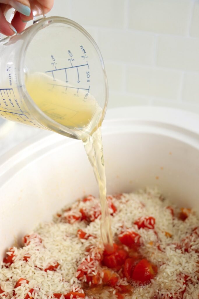 Broth being poured into slow cooker with the other taco chicken and rice ingredients.