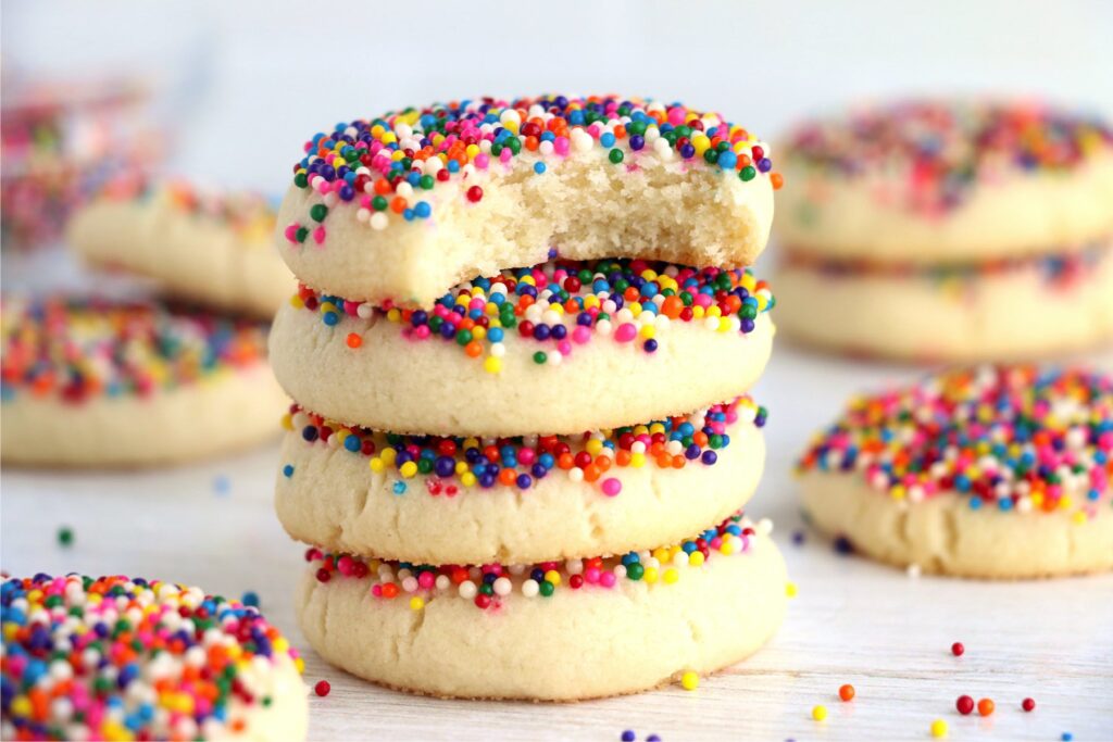 Closeup shot of sprinkle sugar cookies stacked atop one another with bite taken out of top cookie