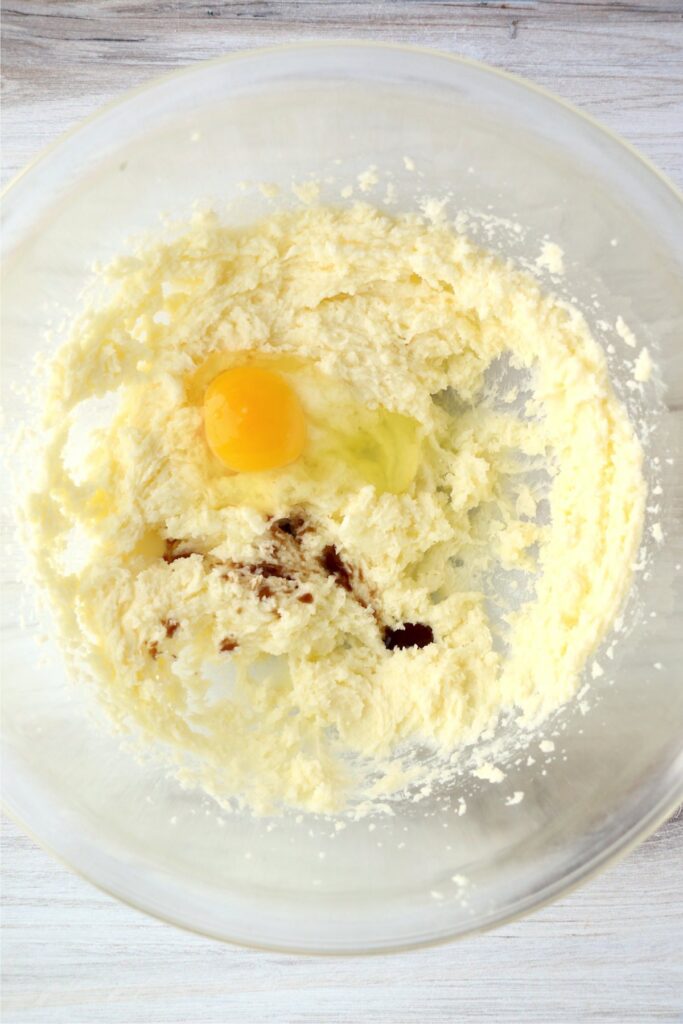 Overhead shot of egg and vanilla with creamed butter and sugar in bowl