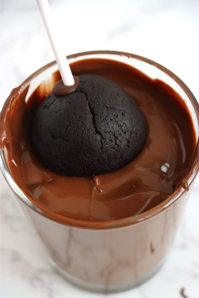 Cake ball being dipped into melted chocolate