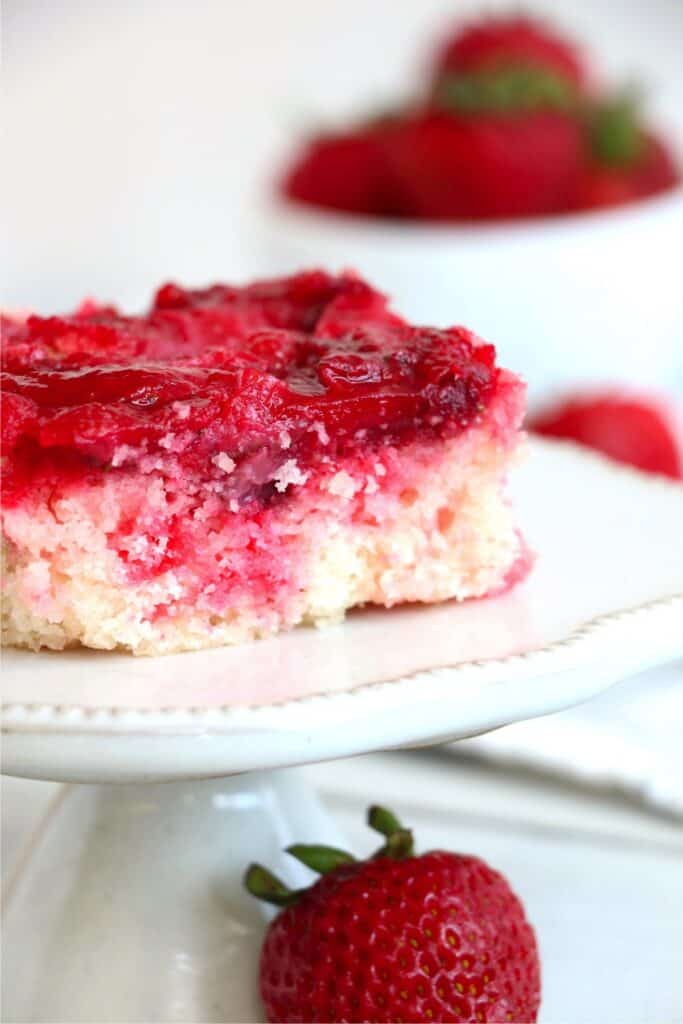 Closeup shot of slice of easy strawberry dump cake on cake stand.