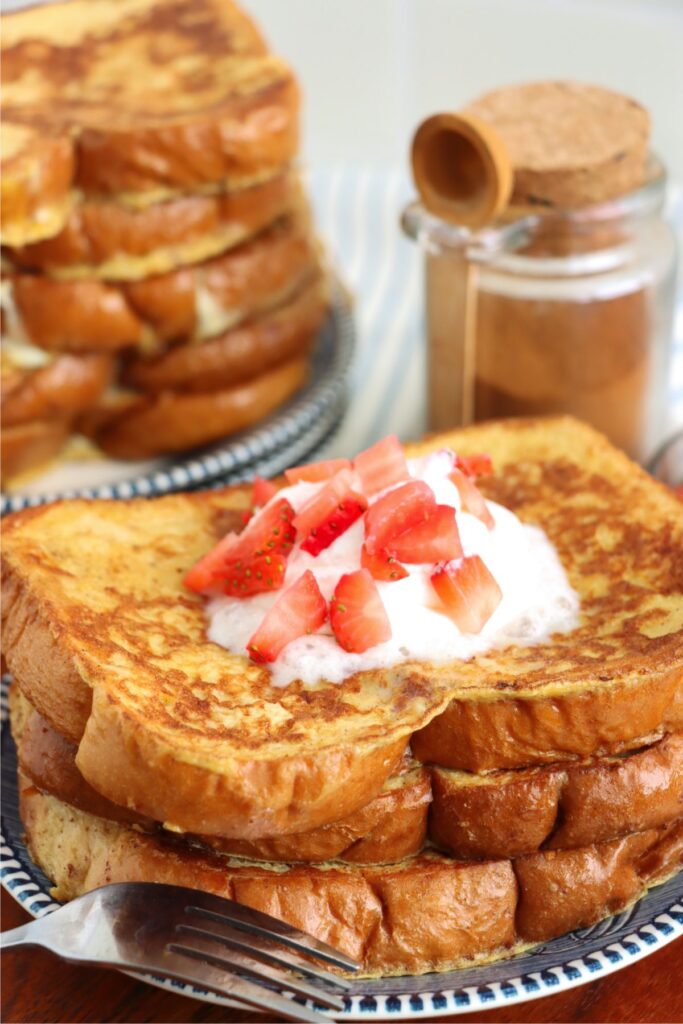 Closeup shot of sweet Hawaiian bread French toast topped with whipped cream and strawberries on plate