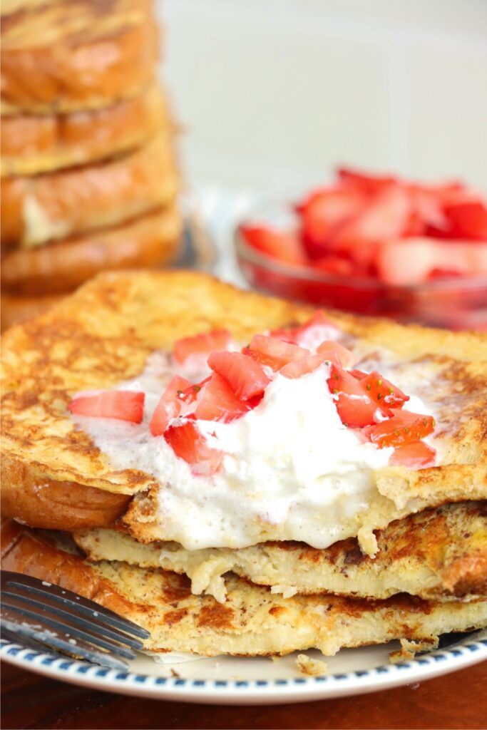 Closeup shot of stack of sweet Hawaiian bread French toast with bite removed on plate