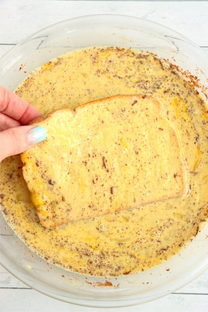 Overhead shot of bread being soaked in French toast egg mixture