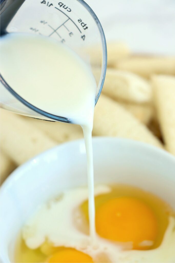 Closeup shot of milk being poured into bowlful of eggs
