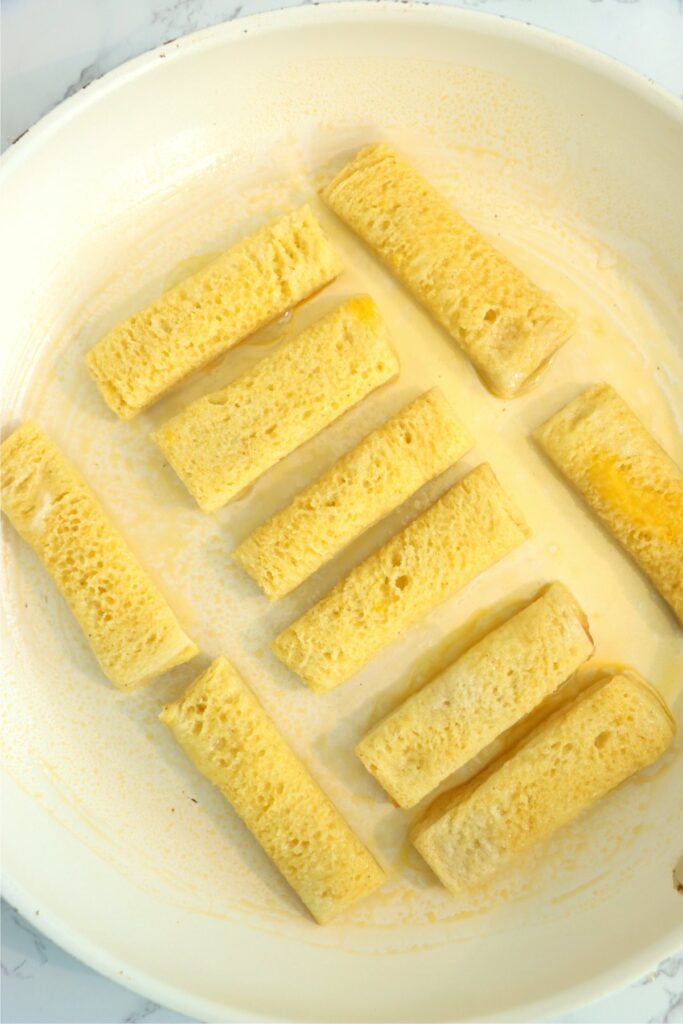 Overhead shot of uncooked French toast sticks in skillet