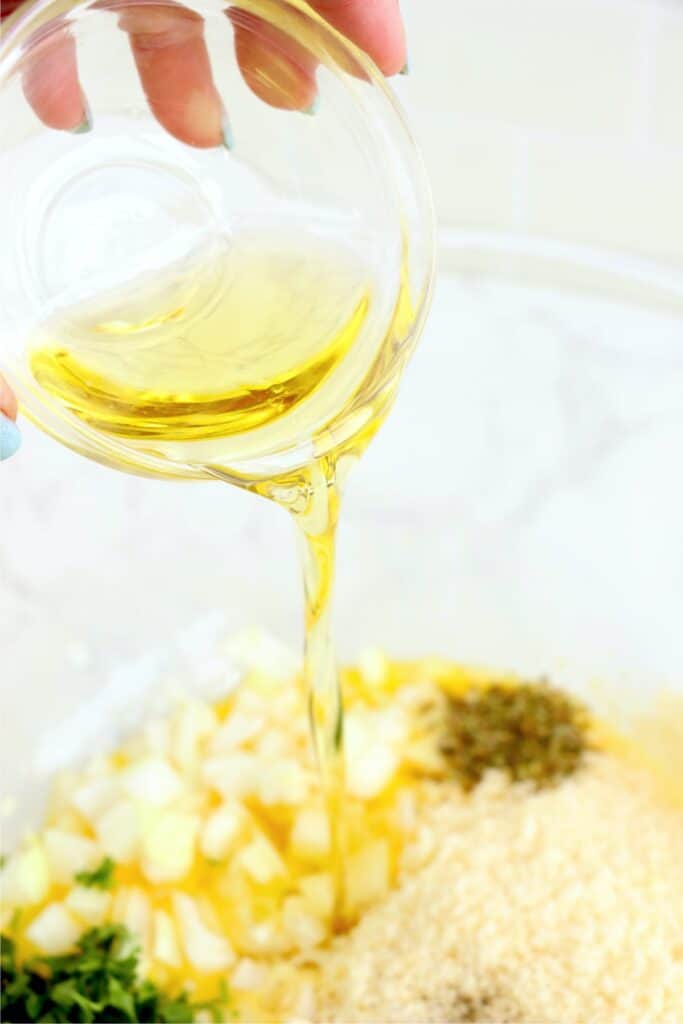 Closeup shot of oil being poured into bowl with other casserole ingredients