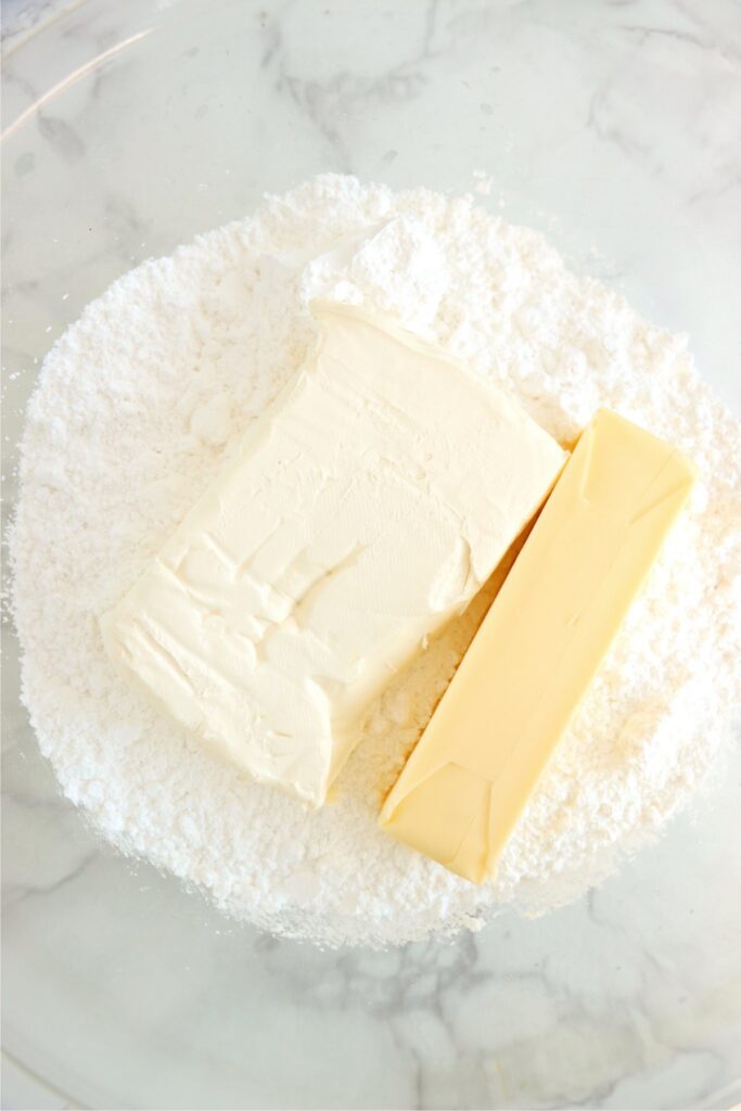 Overhead shot of butter, cream cheese, and powdered sugar in bowl. 