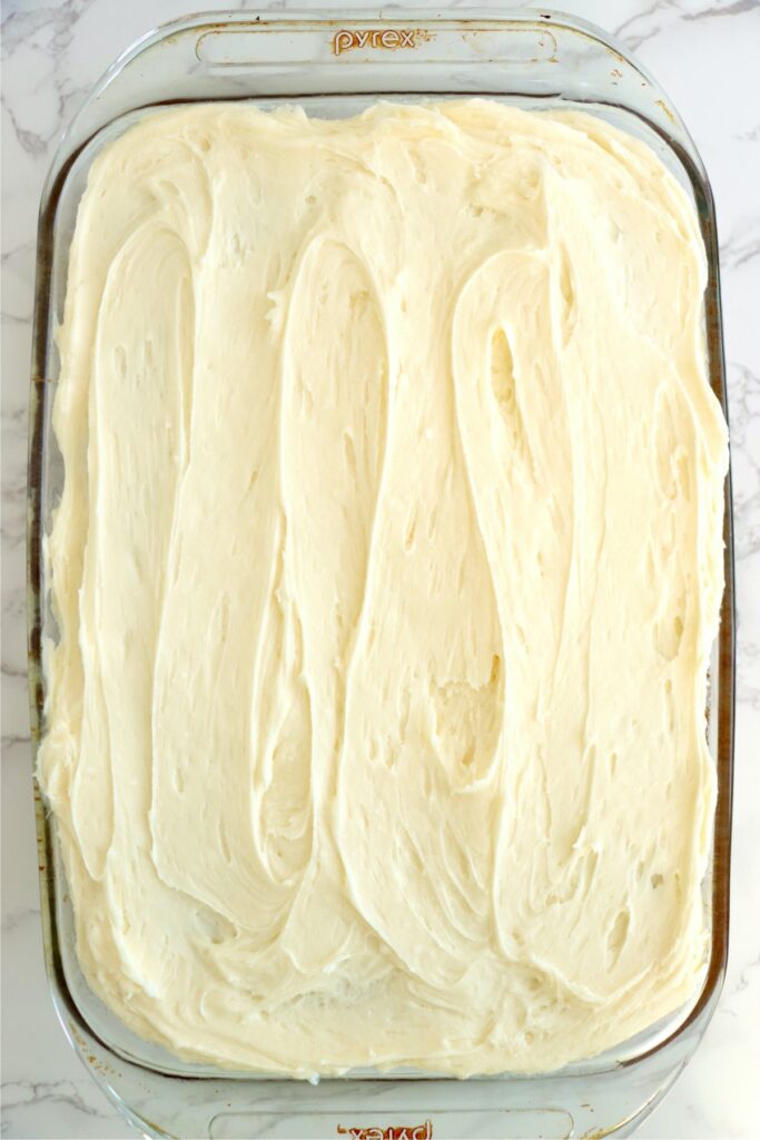 Overhead shot of frosted strawberry banana cake in baking dish. 