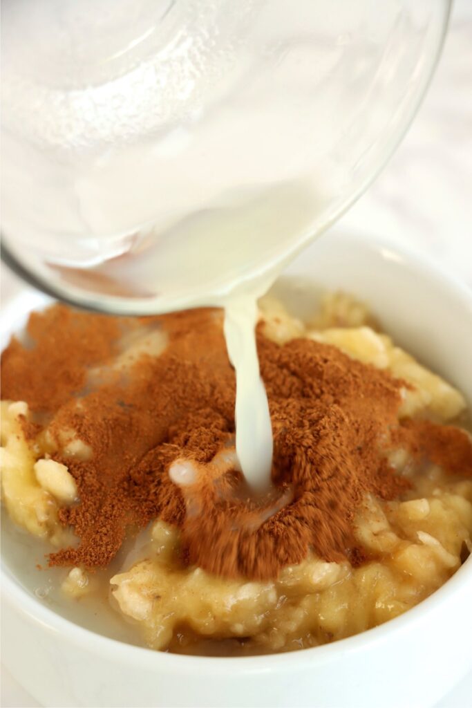 Lemon juice being poured into bowlful of mashed bananas and cinnamon.