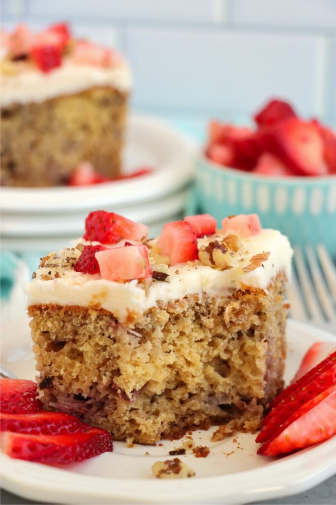 Closeup shot of slice of strawberry banana cake on plate garnished with slices of strawberries. 