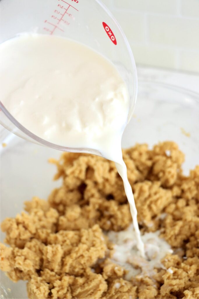 Buttermilk being poured into bowl of flour and sugar mixture. 