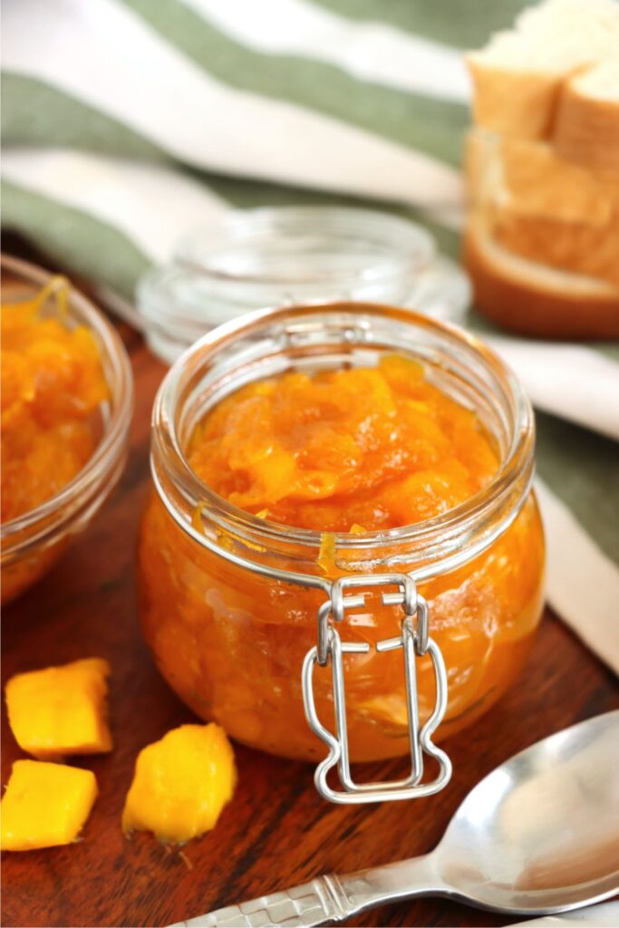 Closeup shot of jar full of homemade mango jam. 