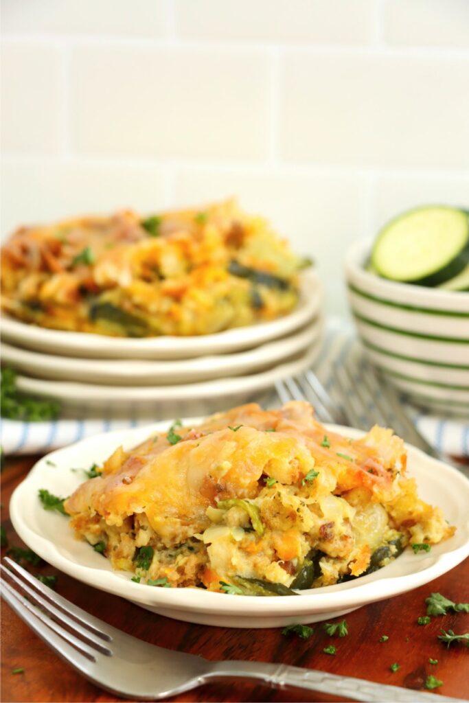 Closeup shot of scoop of old fashioned zucchini casserole on plate with more zucchini casserole on plate in background