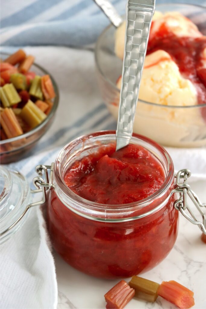 Closeup shot of spoon in jarful of homemade rhubarb sauce.