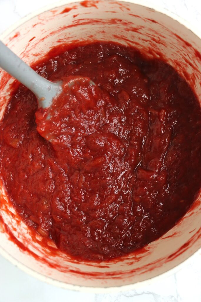 Overhead shot of spatula in saucepan with homemade rhubarb sauce. 