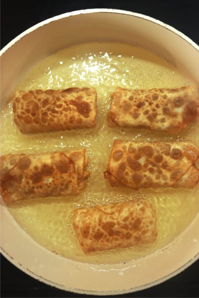 Overhead shot of fried bacon cheeseburger egg rolls in skillet