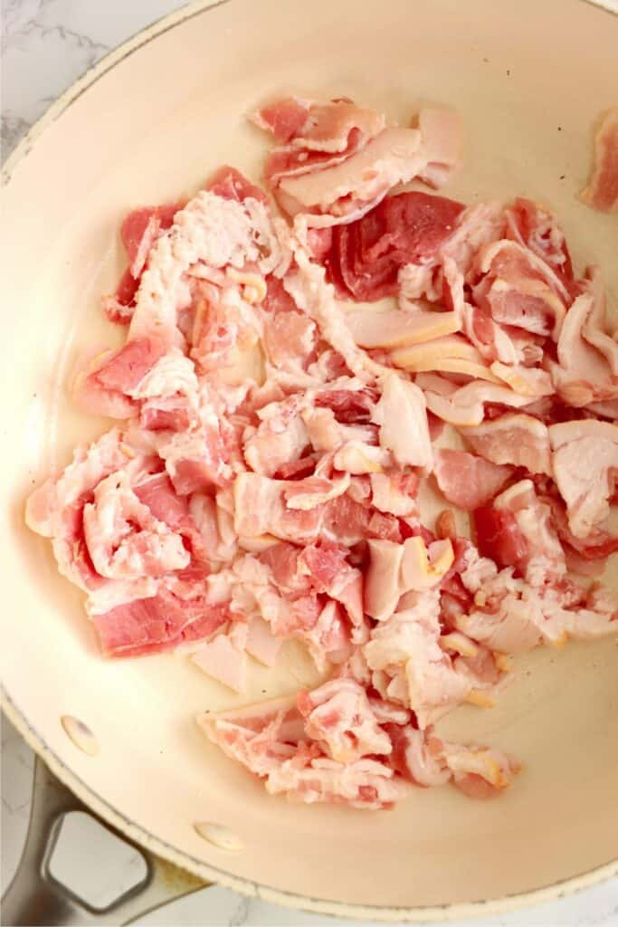 Closeup shot of raw bacon in a skillet.