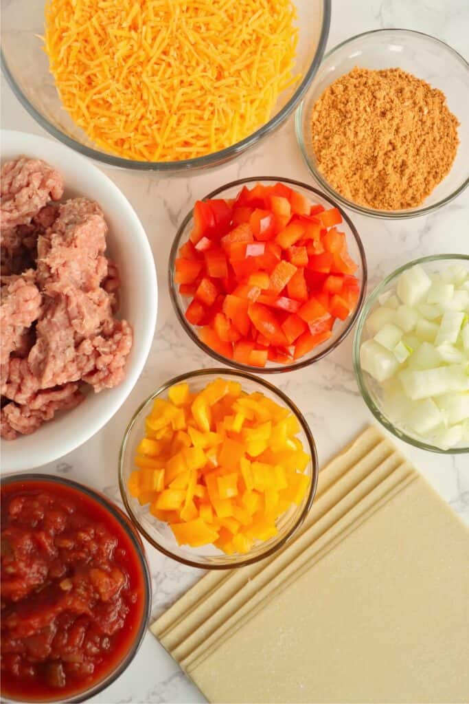 Overhead shot of individual taco egg roll ingredients in bowls on table