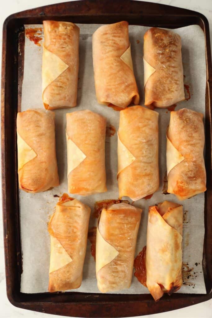 Overhead shot of golden brown taco egg rolls on baking sheet lined with parchment paper