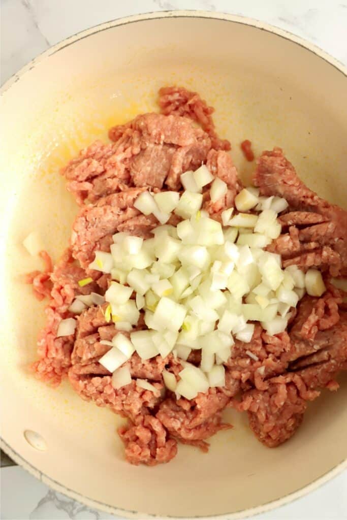 Closeup overhead shot of ground meat and diced onion in skillet