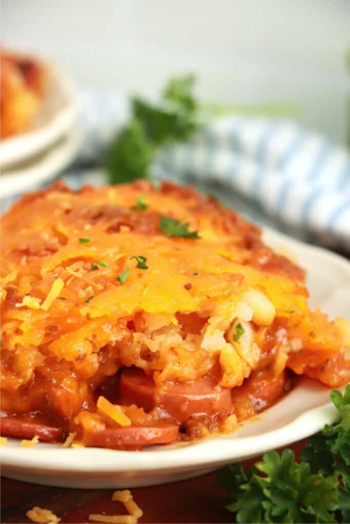 Closeup shot of slice of tater tot hot dog casserole on plate. 