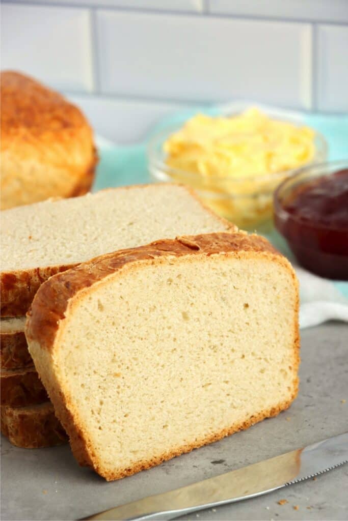 Slice of country white bread leaning against a stack of more bread slices