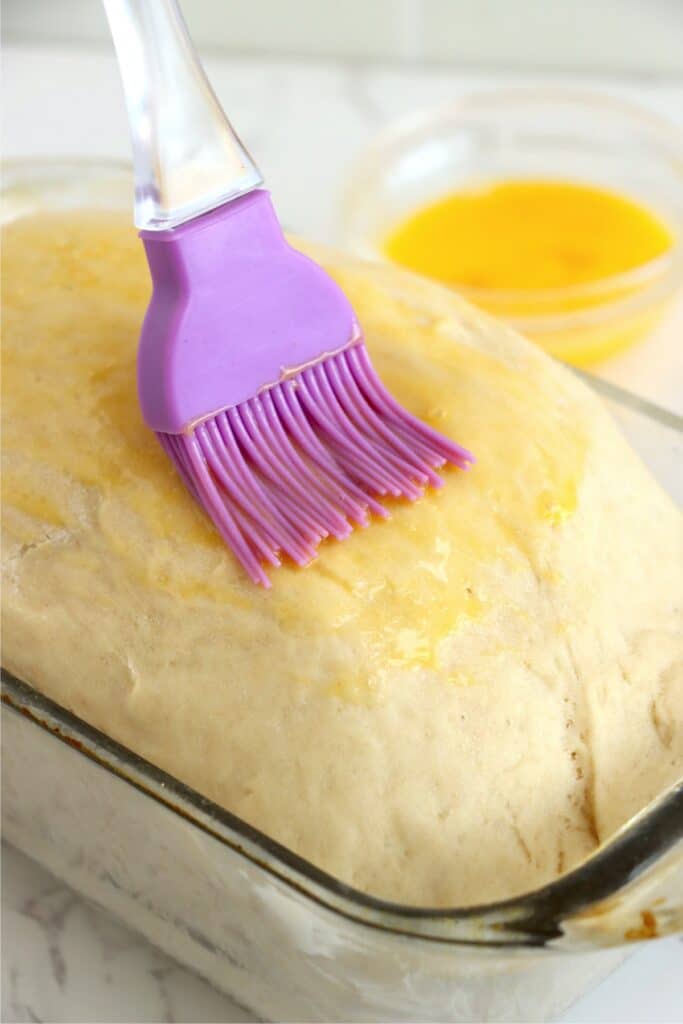 Closeup shot of unbaked loaf of country white bread being brushed with beaten egg