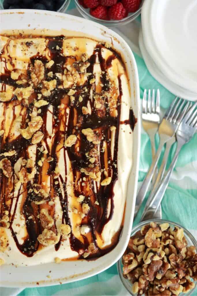 Overhead shot of unset cheesecake toped with syrup and nuts. 