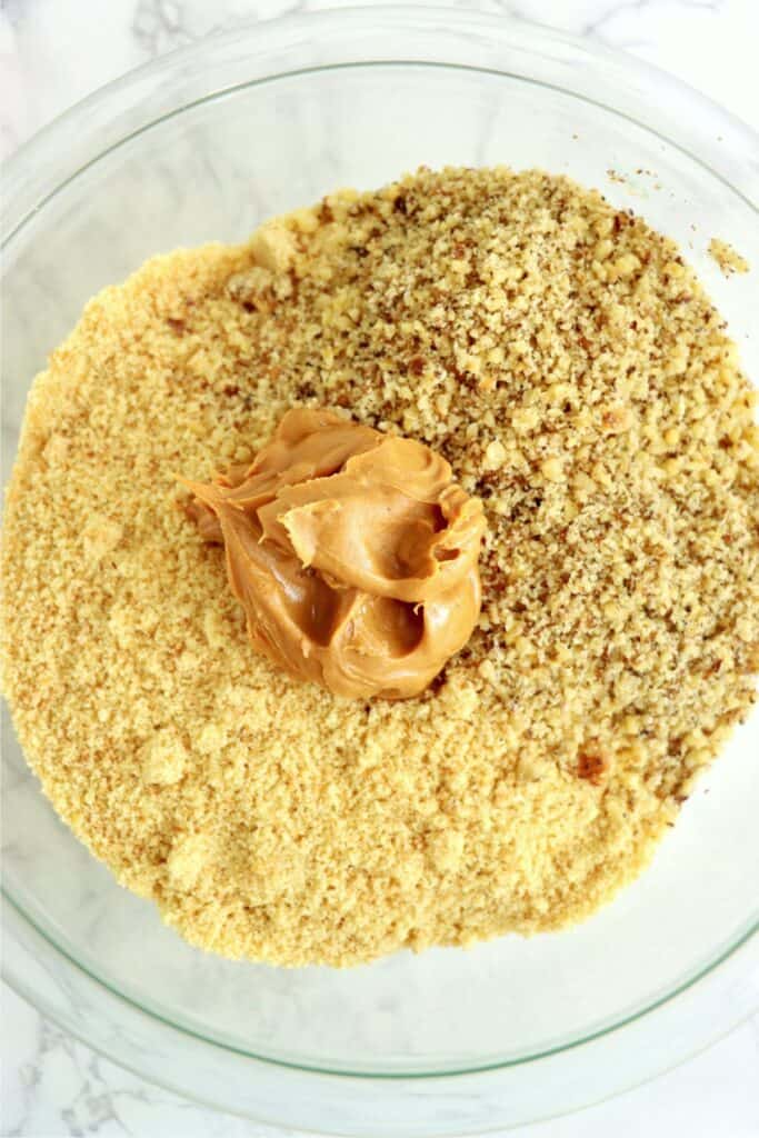 Closeup overhead shot of peanut butter, crushed vanilla wafers, and crushed pecans in bowl. 