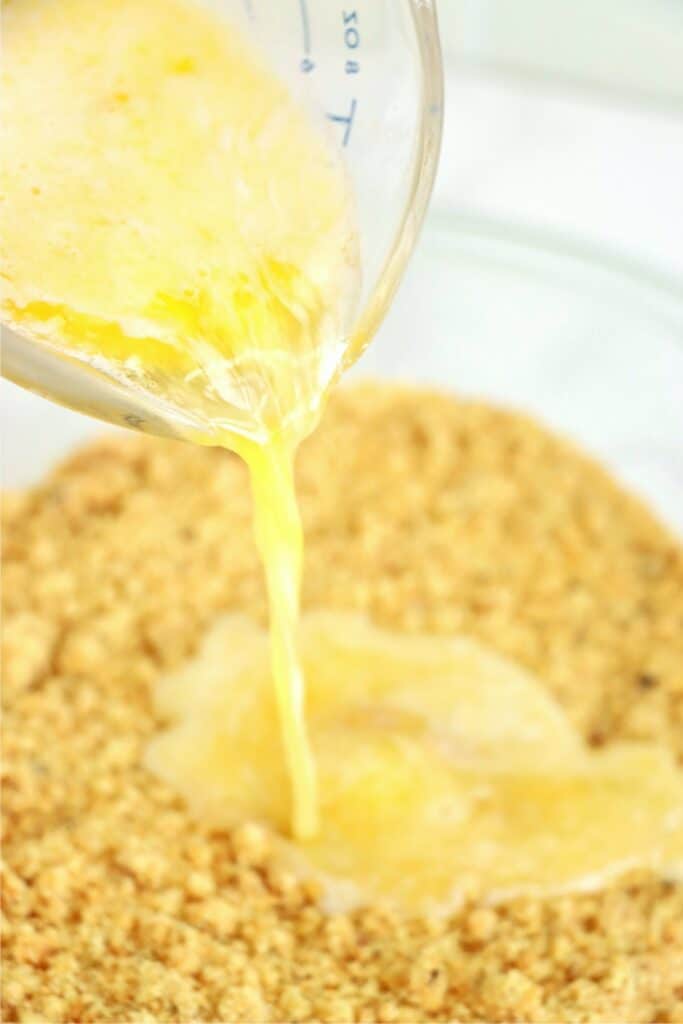 Melted butter being poured into mixture of peanut butter, vanilla wafers, and pecans. 