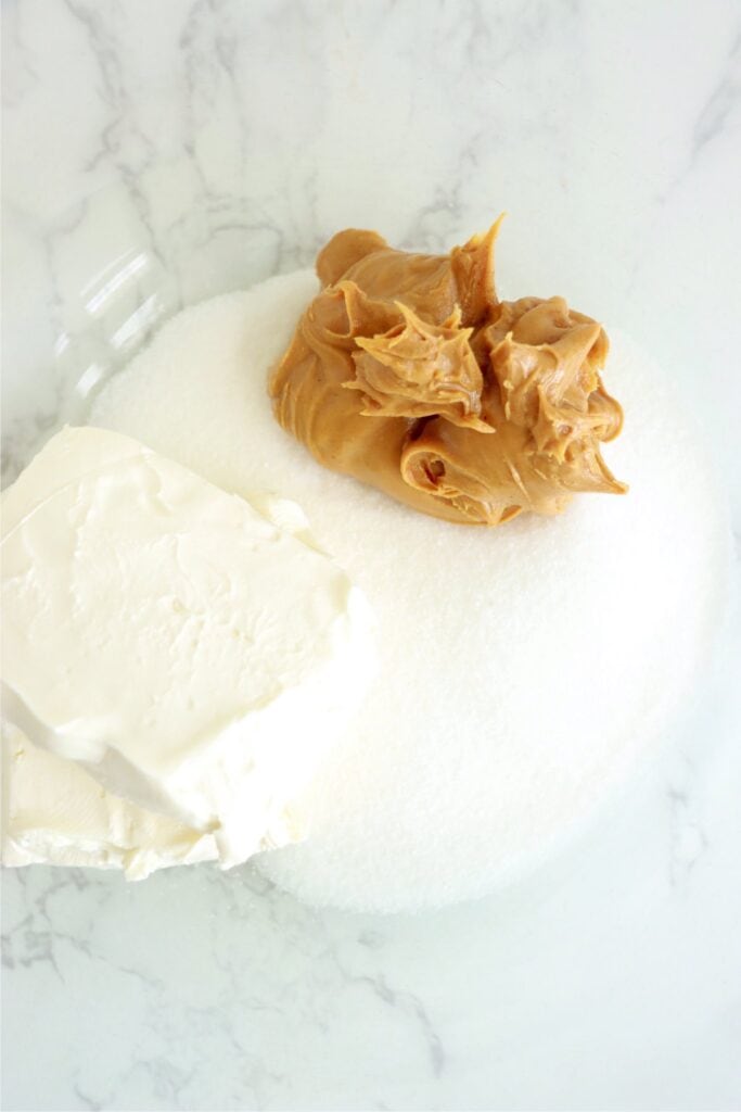 Overhead closeup shot of peanut butter, cream cheese, and sugar in bowl