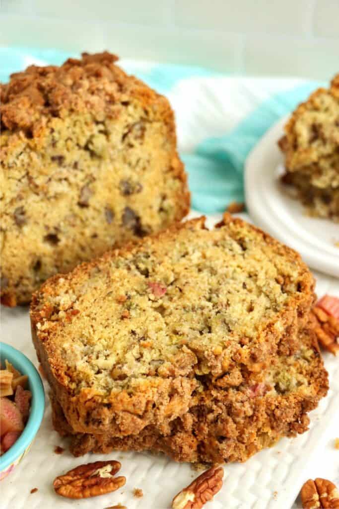 Closeup shot of two slices of rhubarb nut bread on plate with more bread in background