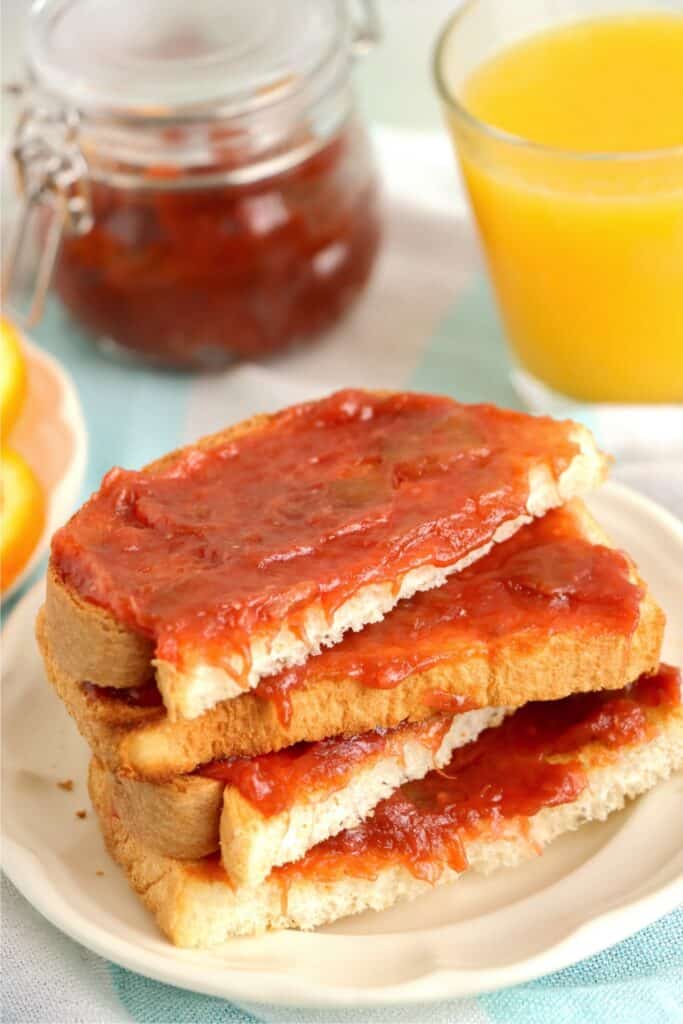 Slices of bread topped with homemade rhubarb jam stacked atop one another on plate.