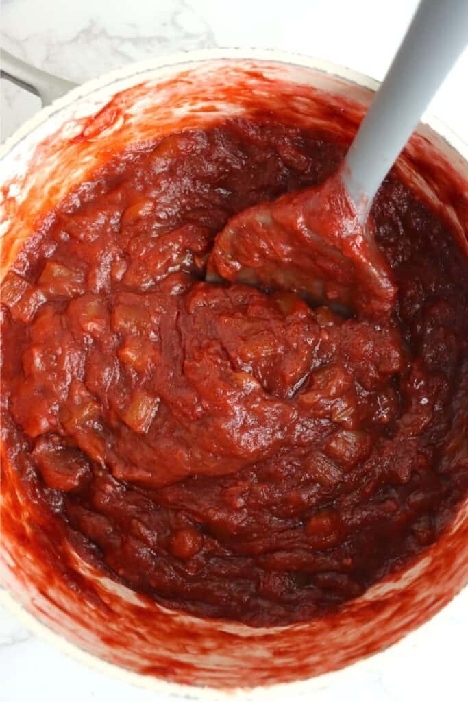 Overhead shot of plastic spoon in potful of homemade rhubarb jam.