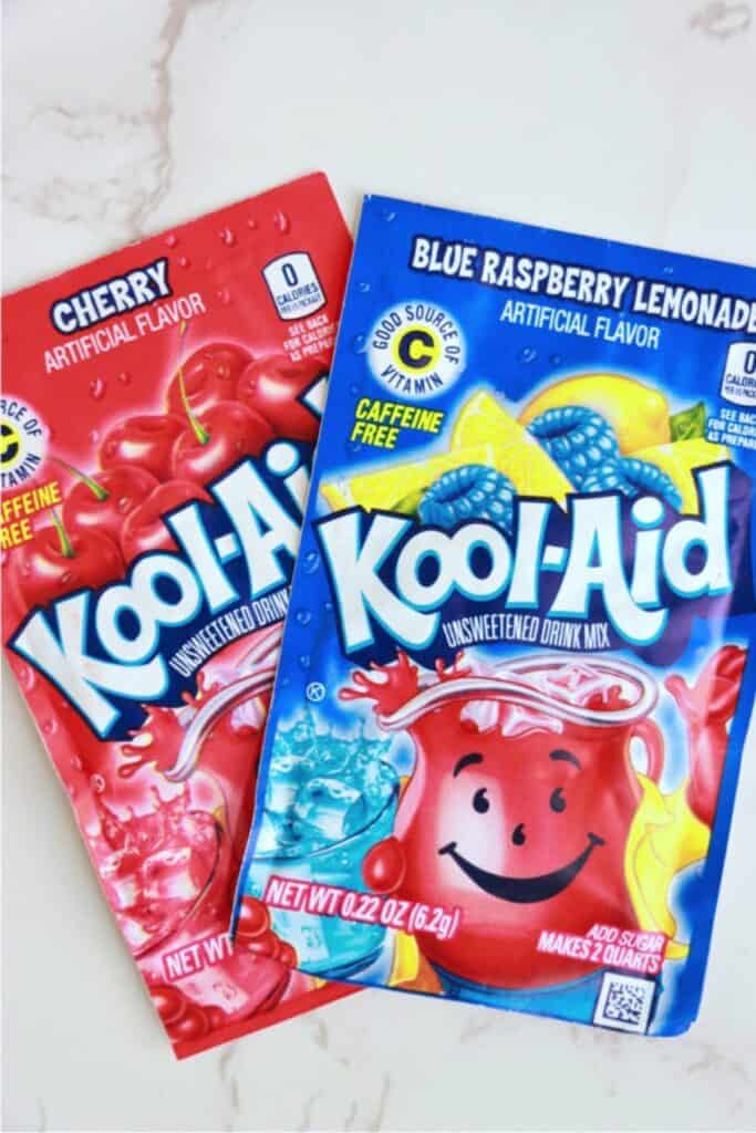 Two packets of Kool Aid mix on table. 