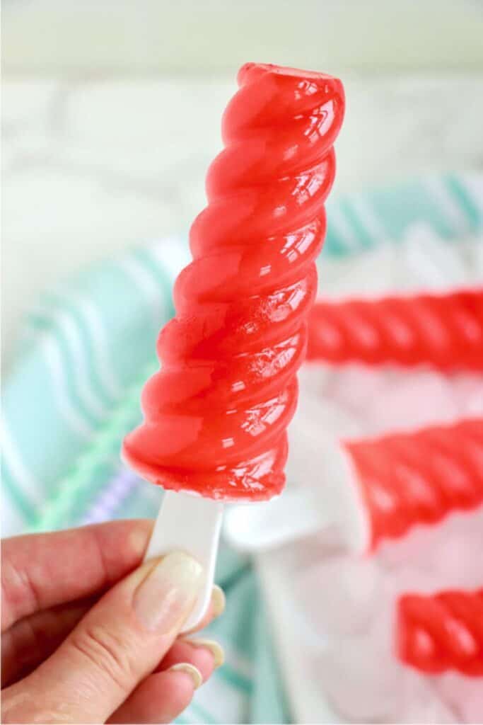 Closeup shot of hand holding a Kool Aid popsicle. 