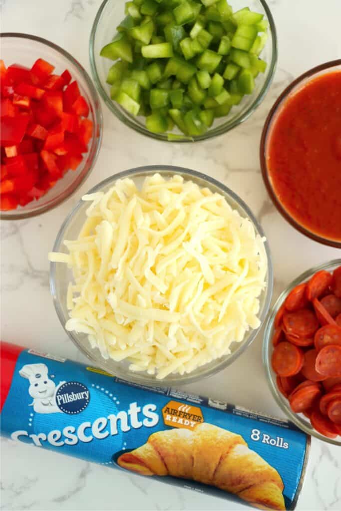 Overhead shot of individual pizza pinwheel ingredients in bowls on table