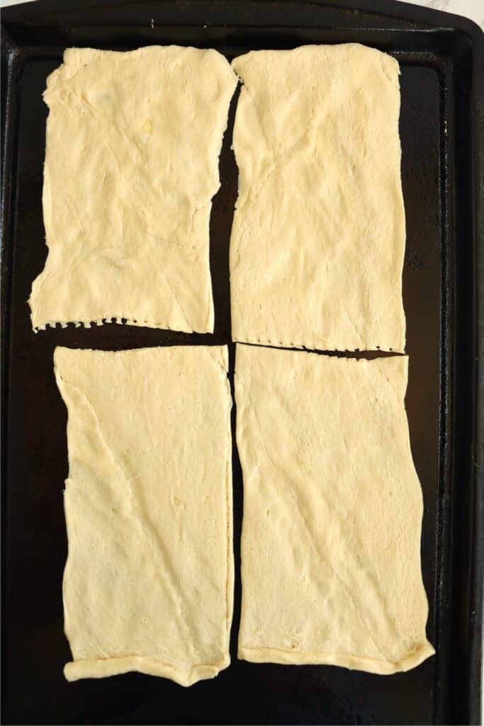 Overhead shot of four crescent dough rectangles on baking sheet. 